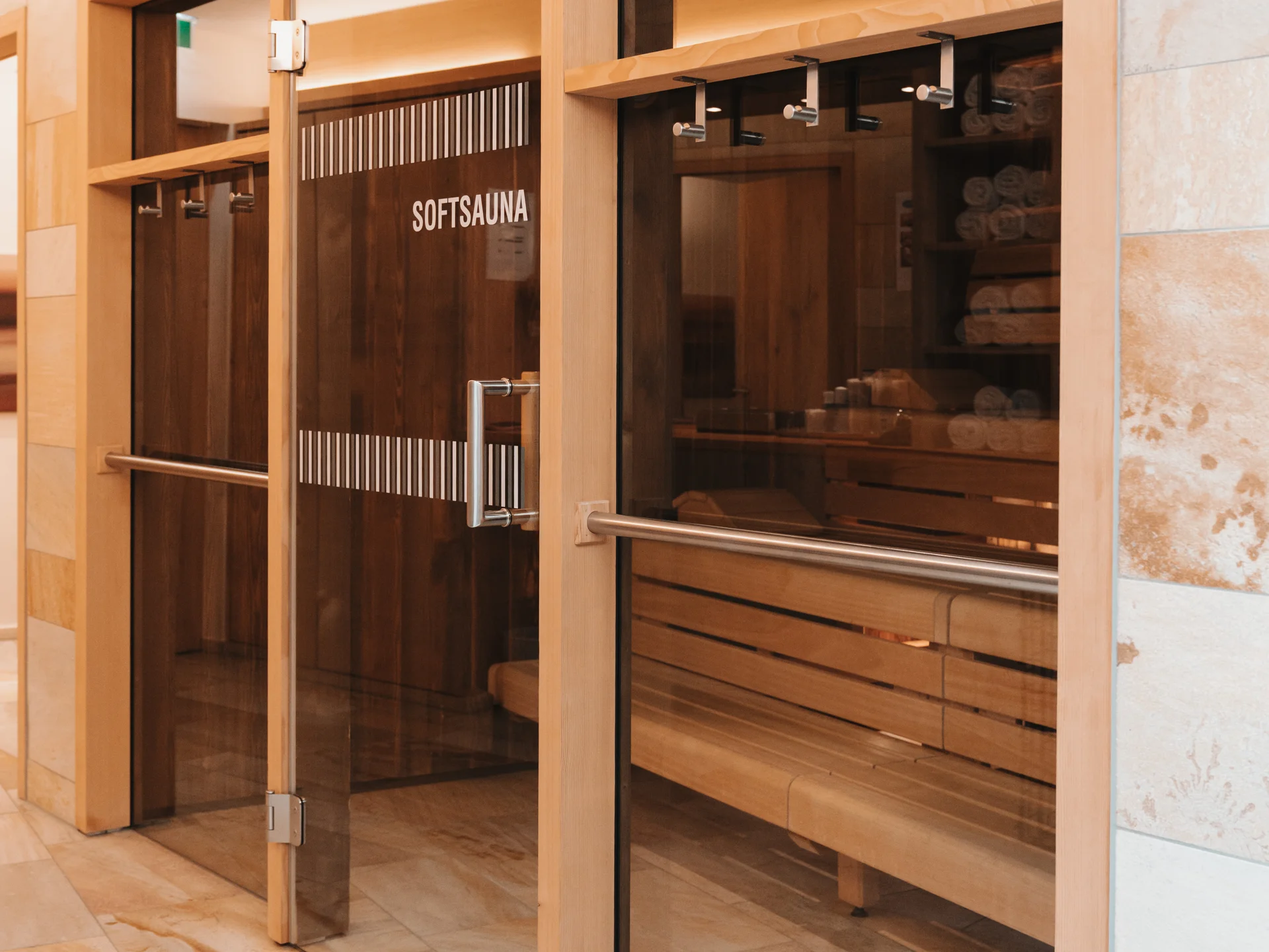 Hotel in Lech am Arlberg mit Ski-in/Ski-out | Hotel Panorama Gläserner Eingang zur Softsauna mit Holzbänken und hellen Steinfliesen