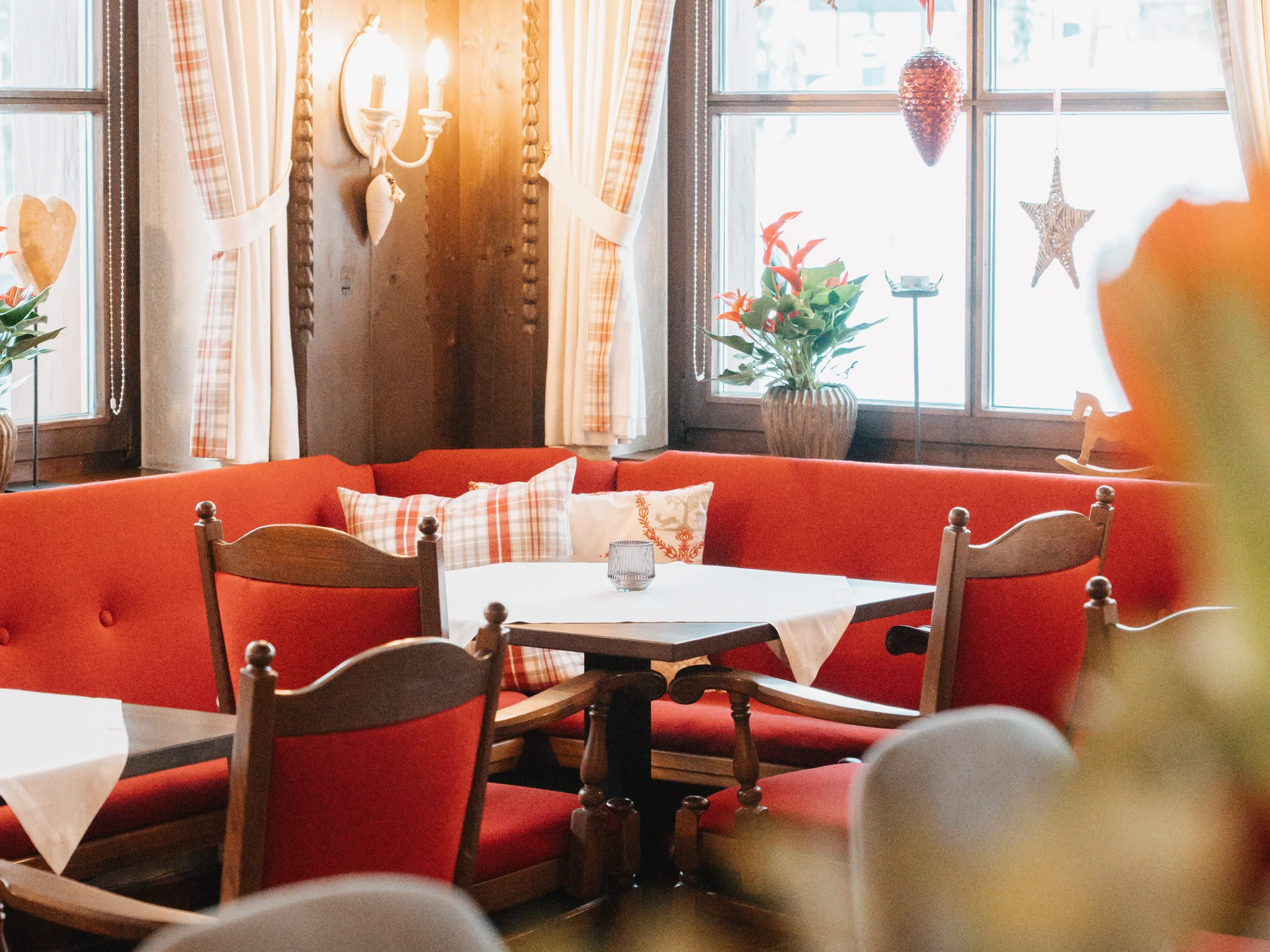 Hotel in Lech am Arlberg mit Ski-in/Ski-out | Hotel Panorama Gemütlicher Gastraum mit roten Sitzbänken, Holztischen und Sternen an den Fenstern