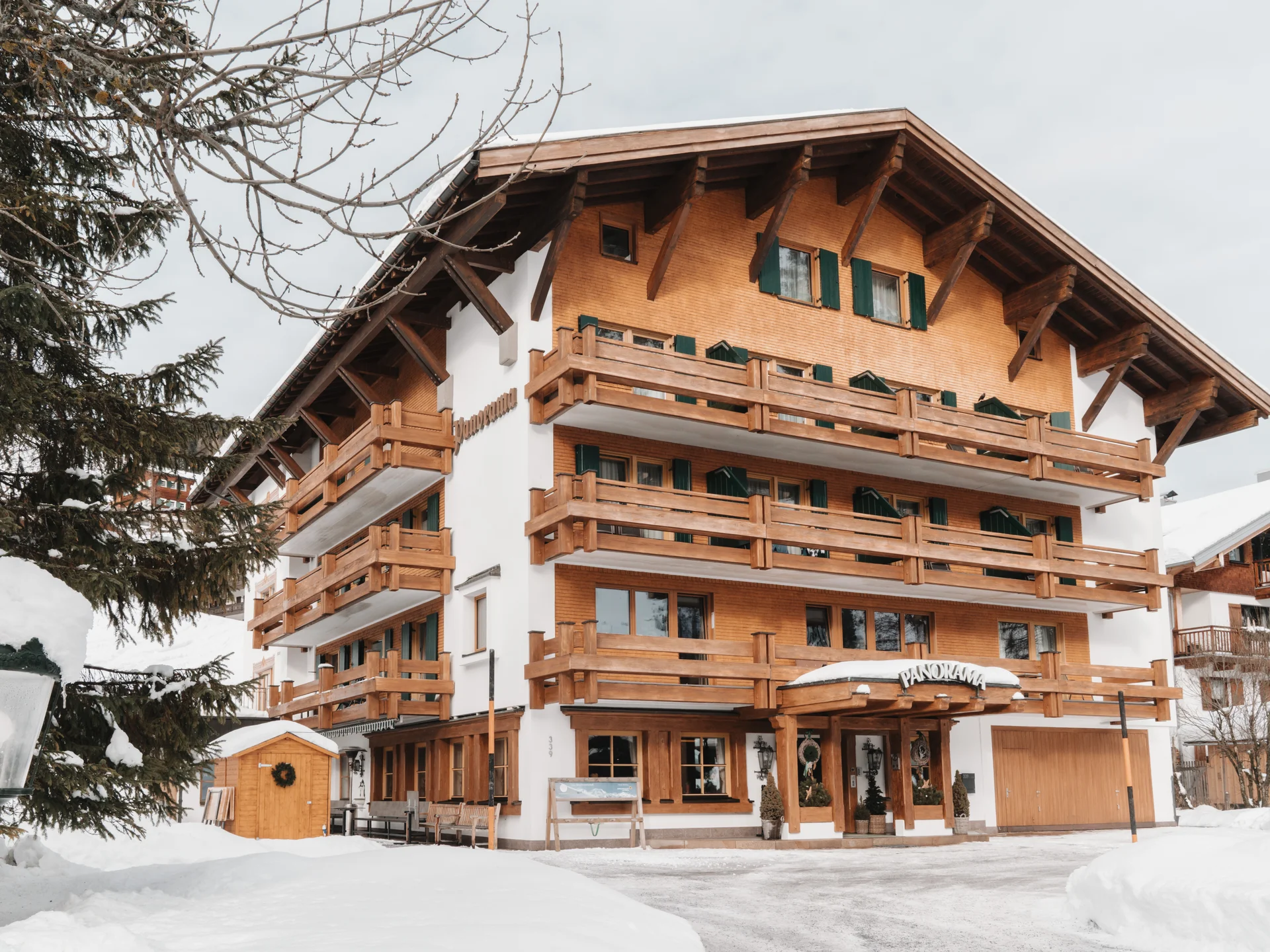 Hotel in Lech am Arlberg mit Ski-in/Ski-out | Hotel Panorama Alpenhaus mit Holzbalkonen und verschneitem Eingangsbereich
