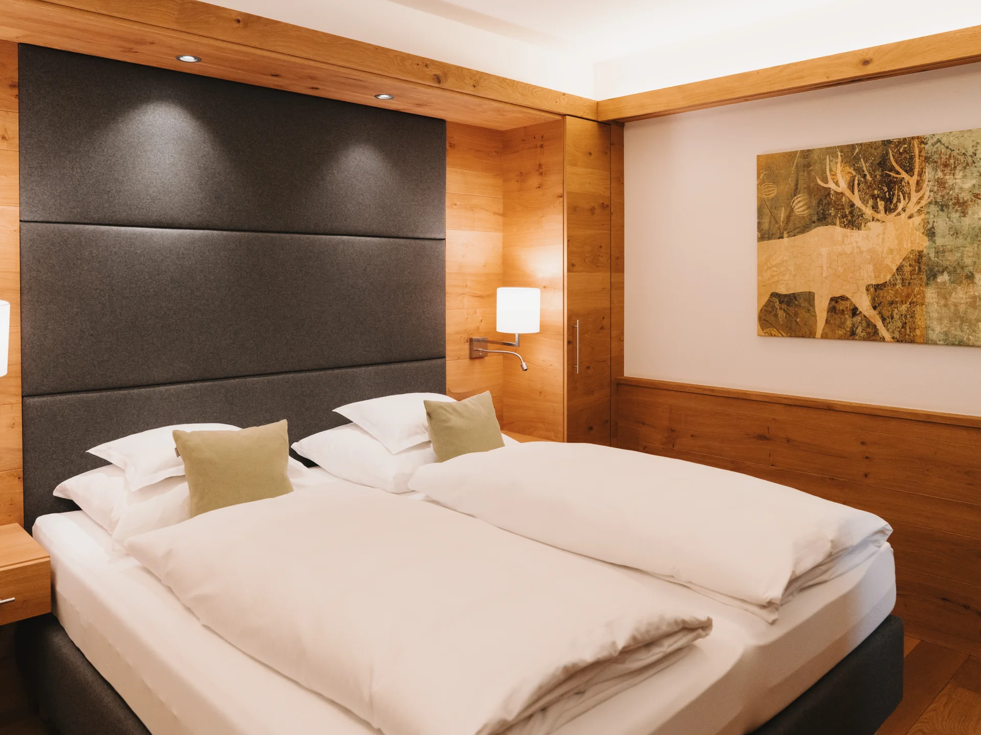 Hotel in Lech am Arlberg mit Ski-in/Ski-out | Hotel Panorama Hotelzimmer mit zwei weißen Betten, dunklem Kopfteil und warmen Holzvertäfelungen