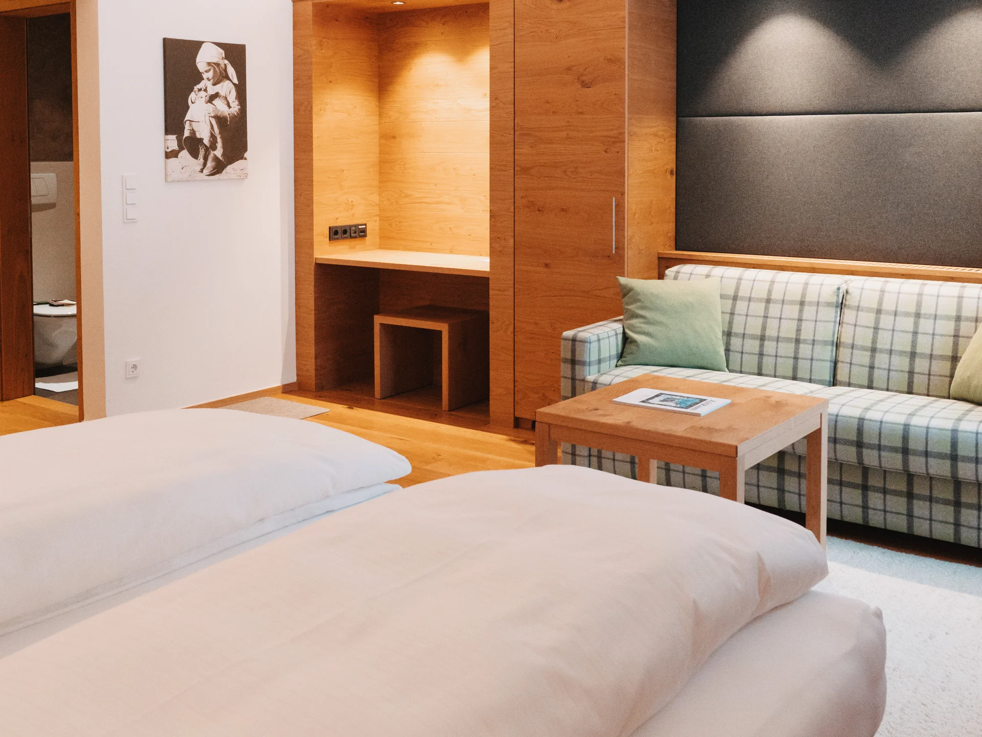 Hotel in Lech am Arlberg mit Ski-in/Ski-out | Hotel Panorama Hotelzimmer mit großem Bett, kariertem Sofa und hölzerner Einbaunische