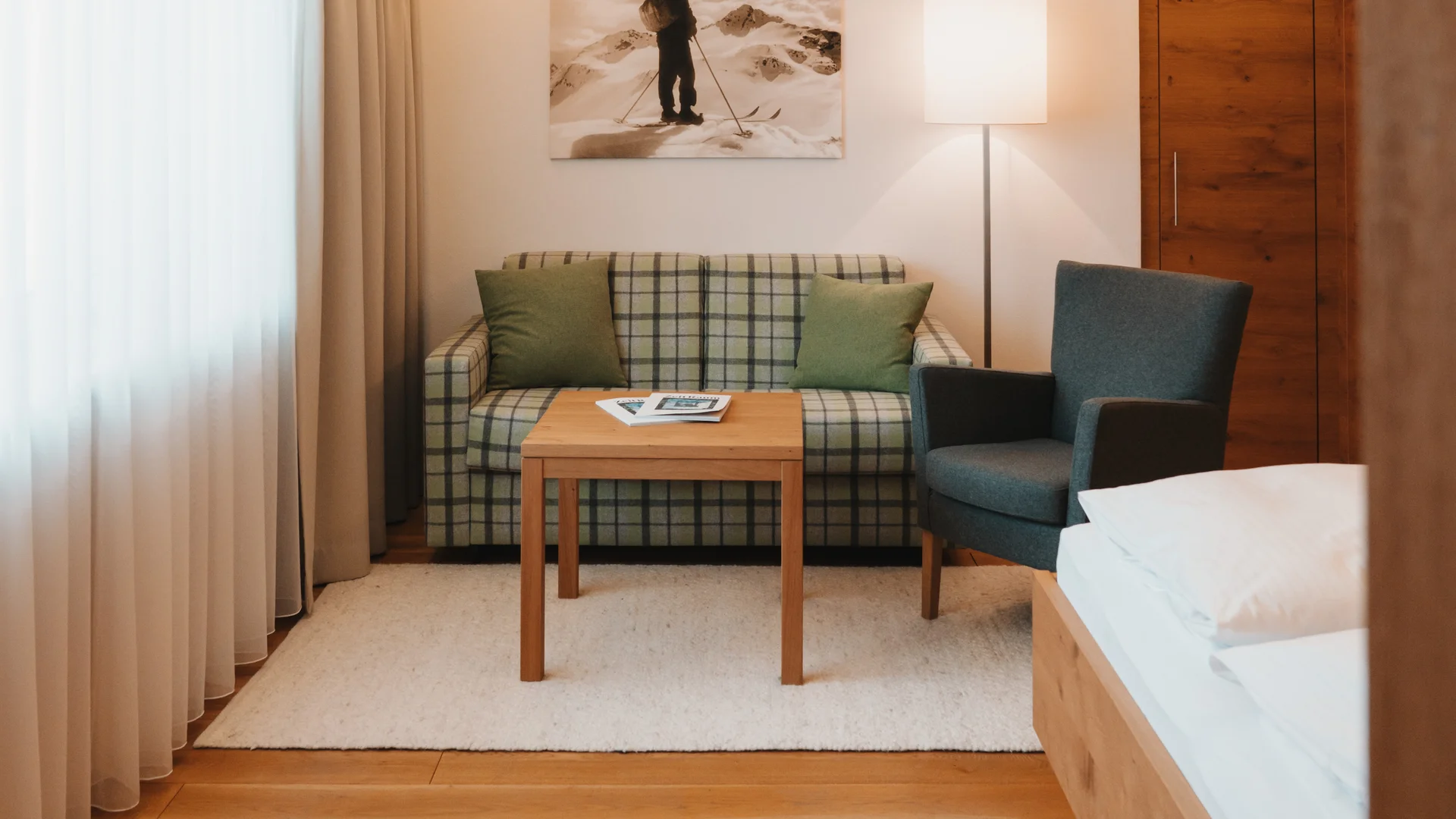 Hotel in Lech am Arlberg mit Ski-in/Ski-out | Hotel Panorama Hotelzimmer mit Bett, kariertem Sofa, Sessel und Holzboden