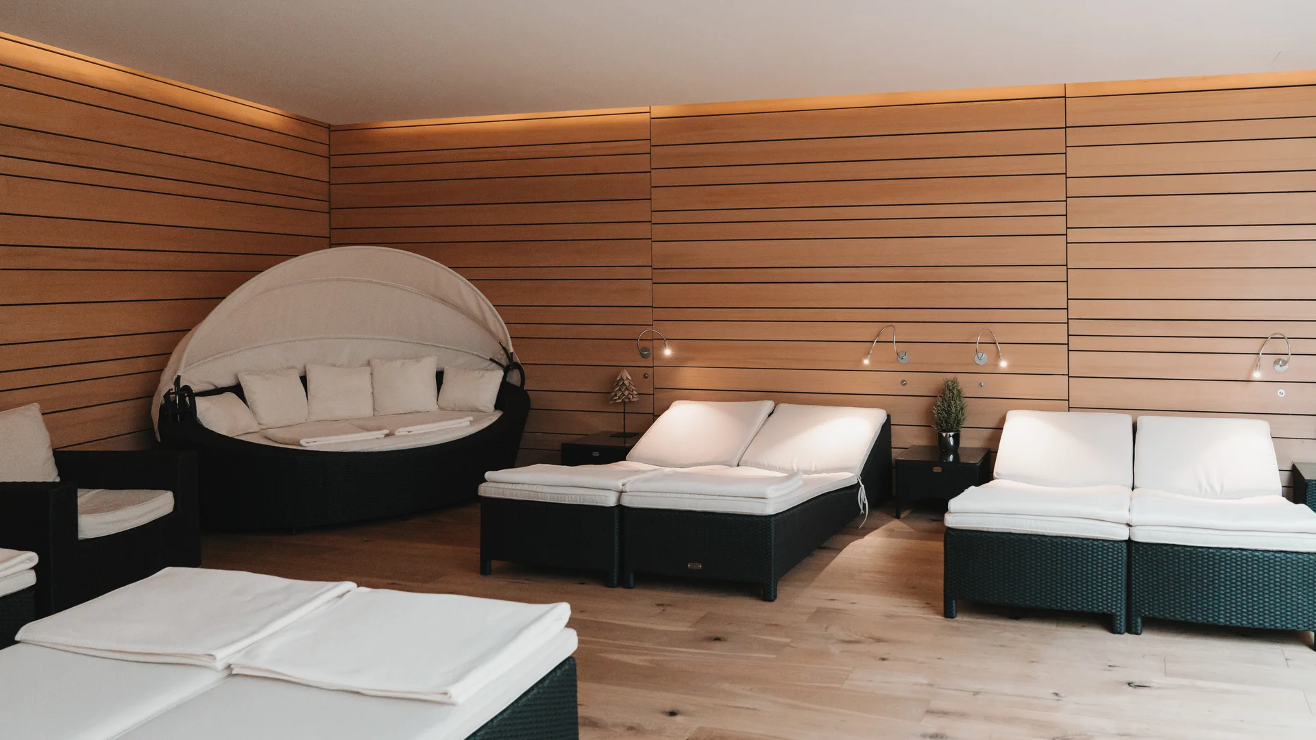 Hotel in Lech am Arlberg mit Ski-in/Ski-out | Hotel Panorama Ruheraum mit weißen Liegen und rundem Daybed vor holzverkleideten Wänden
