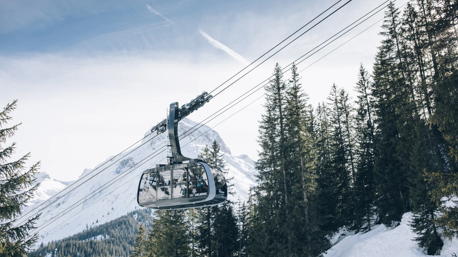 Hotel in Lech am Arlberg mit Ski-in/Ski-out | Hotel Panorama Gondelbahn über verschneite Tannen vor einer alpinen Bergkulisse