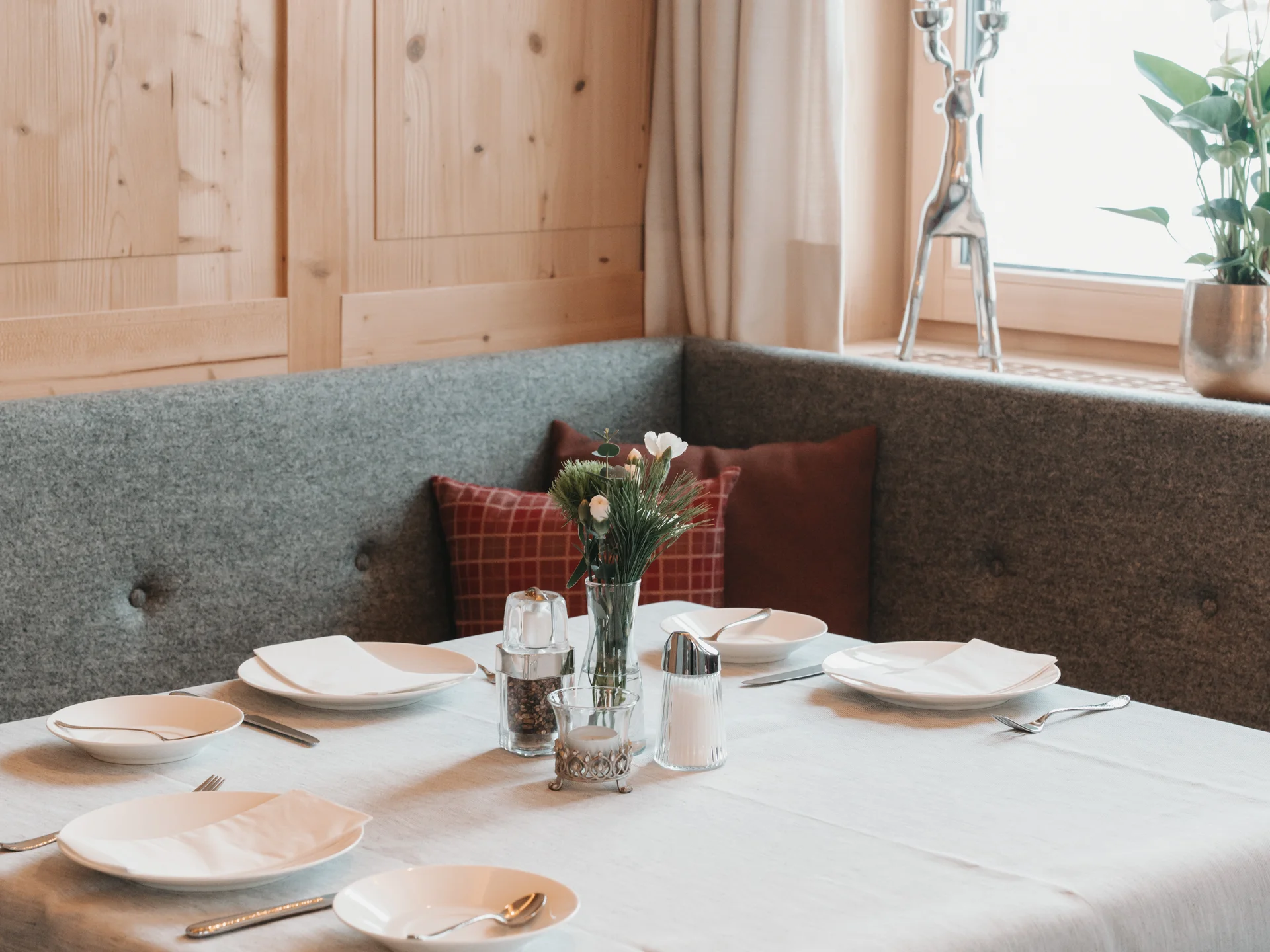 Hotel in Lech am Arlberg mit Ski-in/Ski-out | Hotel Panorama Gedeckter Tisch in einer gemütlichen Sitzecke mit Holzverkleidung und Blumen