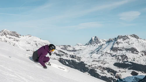 Hotel in Lech am Arlberg mit Ski-in/Ski-out | Hotel Panorama Skifahrer fährt in tiefer Hocke einen verschneiten Hang vor alpiner Bergkulisse hinunter